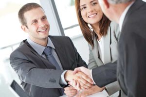 business man shaking hands with male and female clients business people looking at charts and graphs Olson, Reyes & Sauerwein, LLC